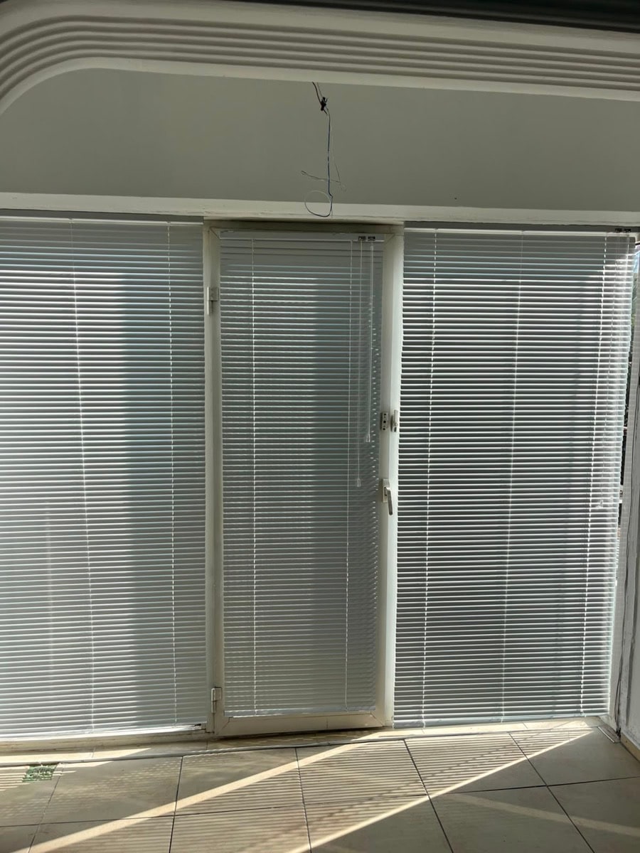 Balkon kapısı ve yanındaki camlarda beyaz metal jaluzi